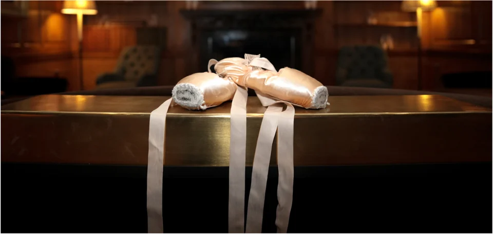 Ballet pointe shoes resting on a piano in a music room